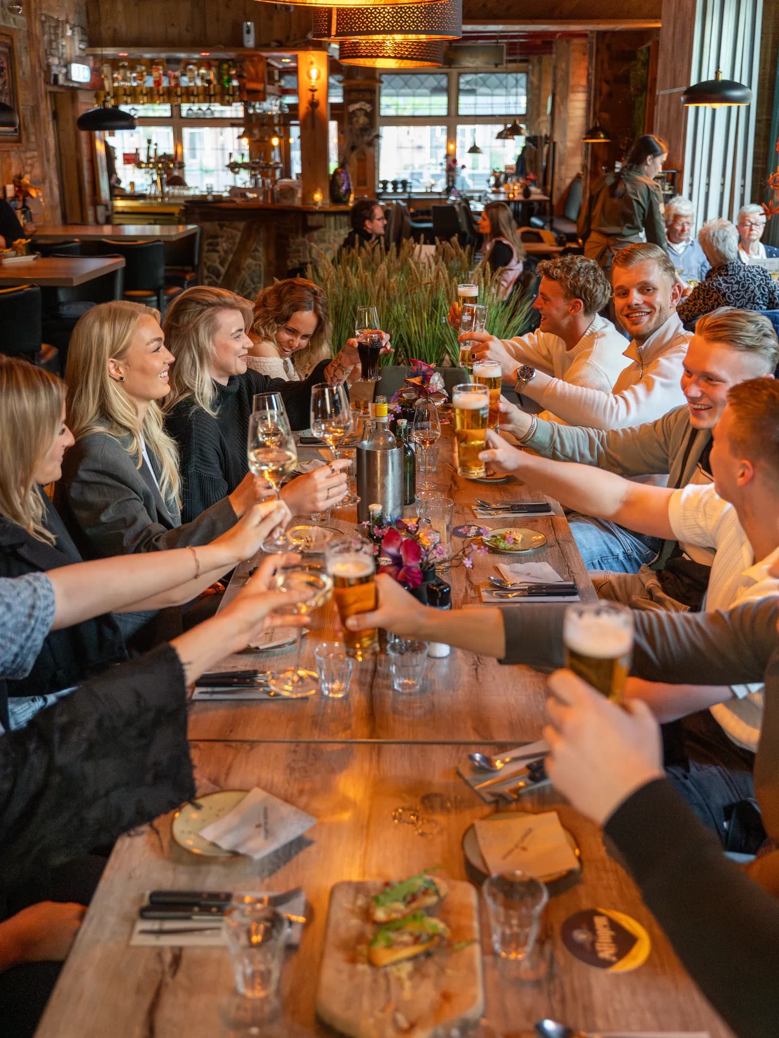 Groep proost samen aan een lange tafel in de gastrobar